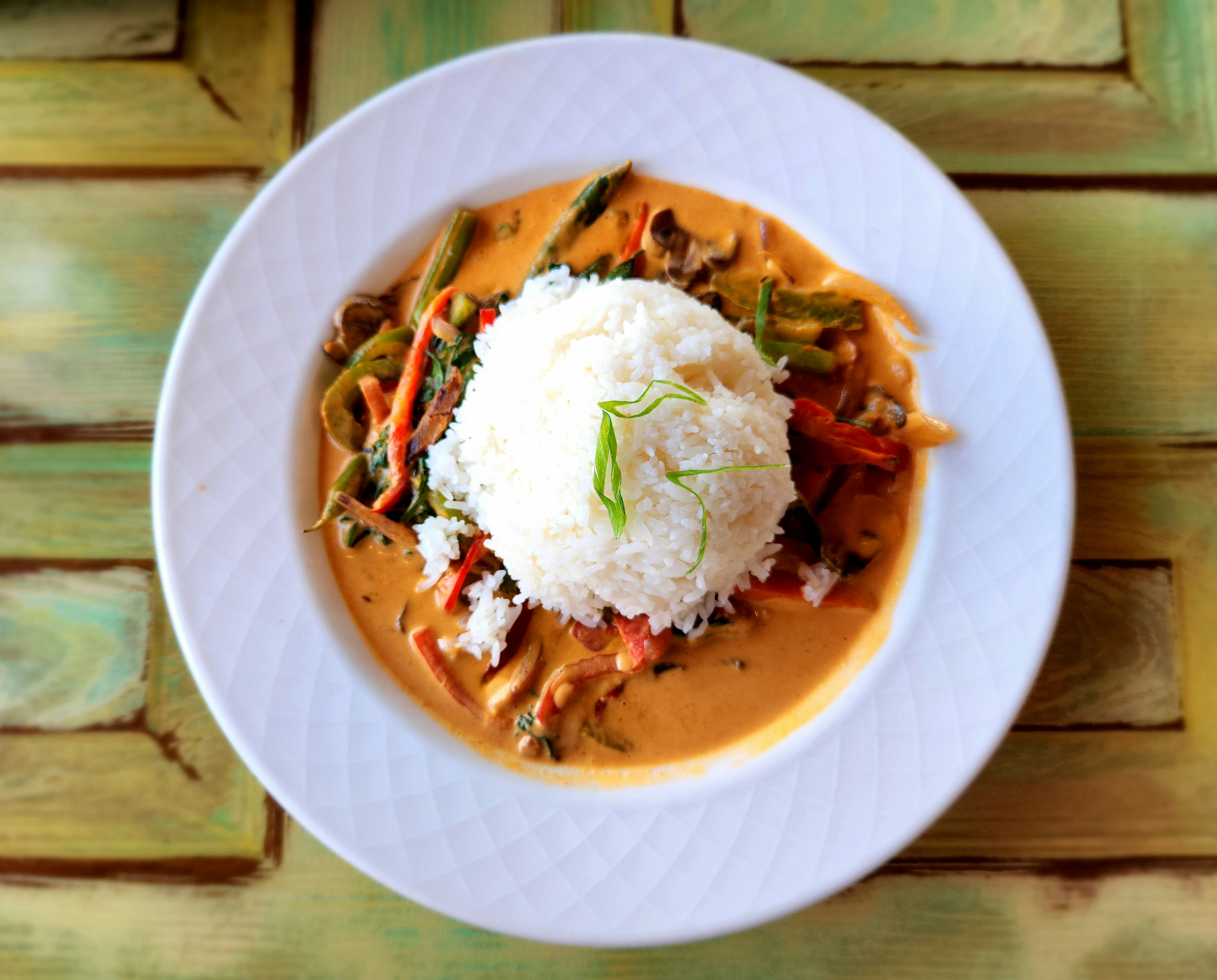A bowl of Thai red curry with chicken, vegetables, and bell peppers